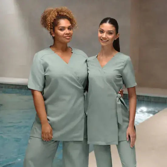 Two ladies wearing green beauty tunics from La Beeby The tunics are supplied by The Staff Uniform Company