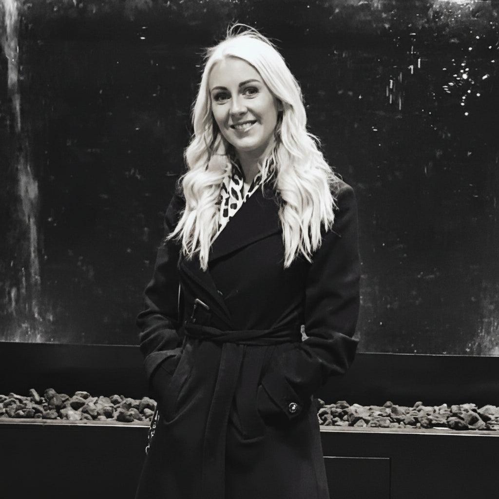 Woman in a black coat standing in front of a large aquarium with decorative planters.