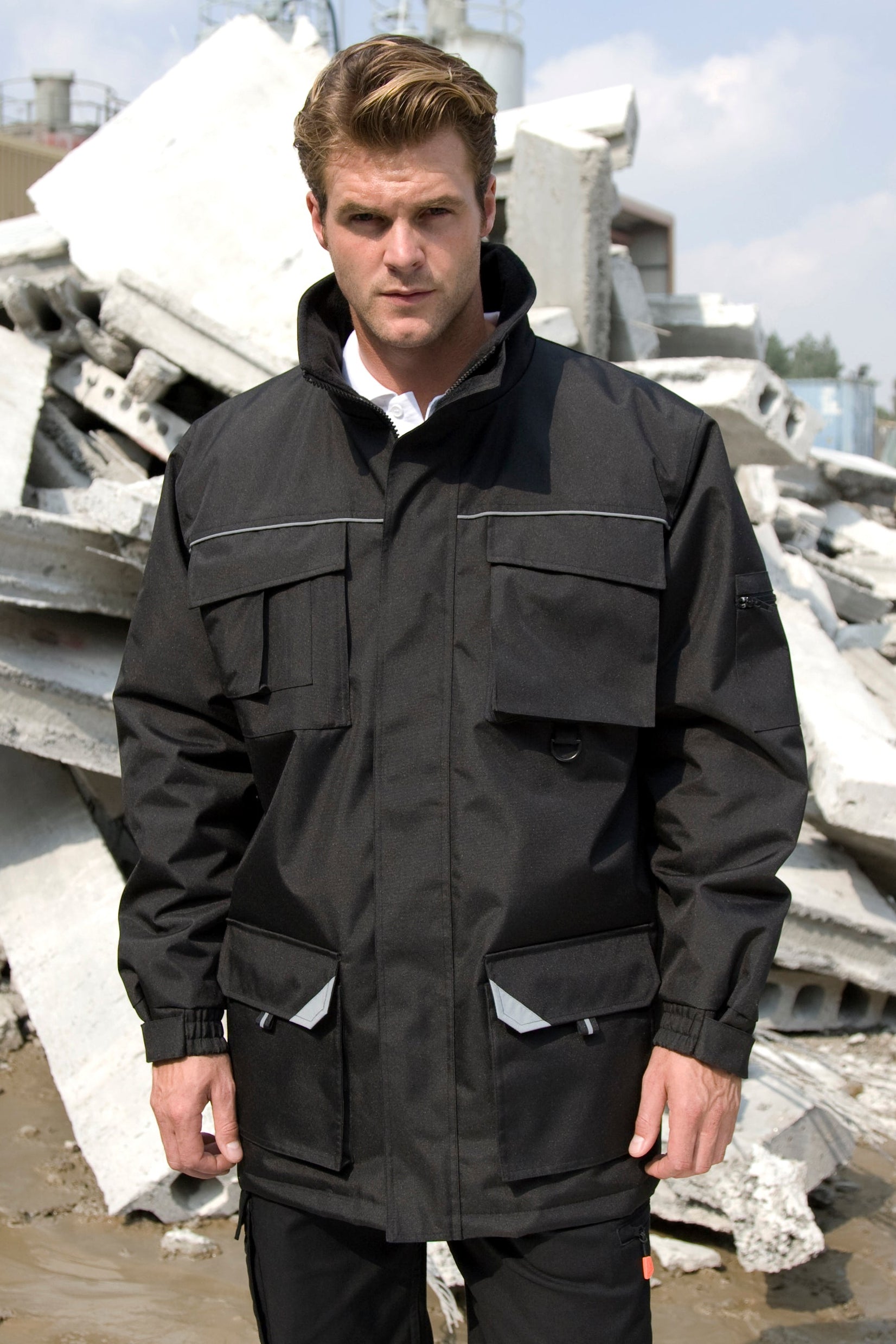 Man wearing a black jacket standing in front of construction debris.